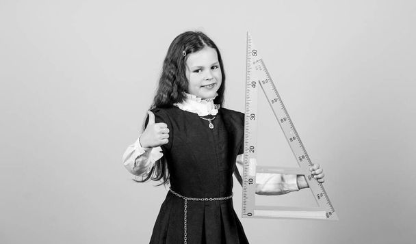 I love mathematics. Smart and clever concept. Pupil cute girl with big ruler. School student study geometry. Sizing and measuring. Kid school uniform hold ruler. Education and school concept - Foto, imagen