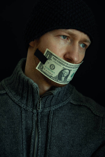 Konzeptbild von Korruption und Bestechung. Schweigen für Geld. Porträt eines Mannes mit geschlossenem Mund und einem Ein-Dollar-Schein.  - Foto, Bild