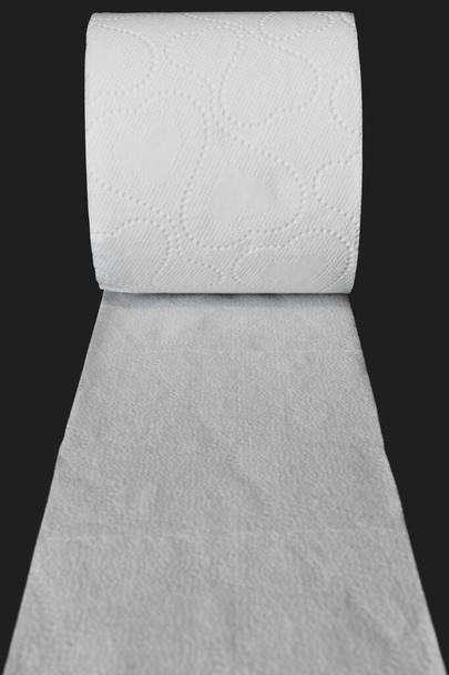 Açılmış beyaz tuvalet kağıdı, fotokopi alanı ile siyah mat arkaplanı üzerinde yuvarlanıyor - Fotoğraf, Görsel