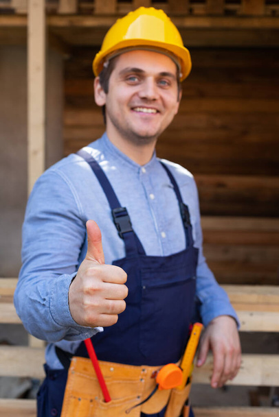 Portrait of a confident young workman wearing yellow helmet, blue uniform - DIY renovation concept - Fotoğraf, Görsel