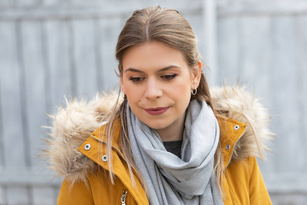 Portrait of an attractive young woman wearing yellow parka jacket outdoor - Фото, зображення
