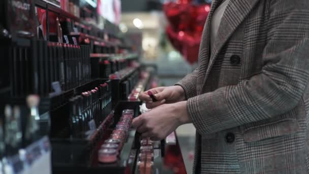 decoratieve cosmetica winkel, vrouwelijke koper test lippenstift en zet het op haar hand tijdens de verkoop - Video