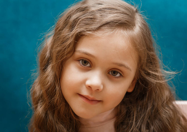 portré egy töprengő kislány hosszú haj a kék háttér - Fotó, kép