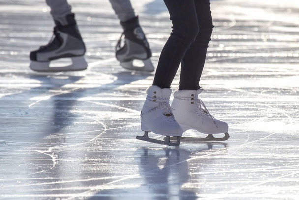 voeten van verschillende mensen die schaatsen op de ijsbaan - Foto, afbeelding