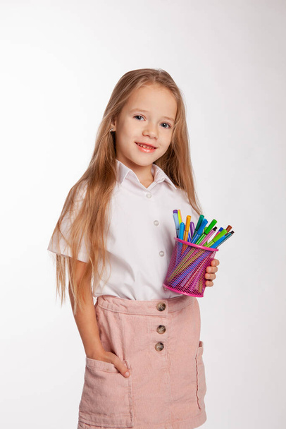 girl stands and holds a jar of felt-tip pens in her hands. Studio bright portrait. - Photo, Image