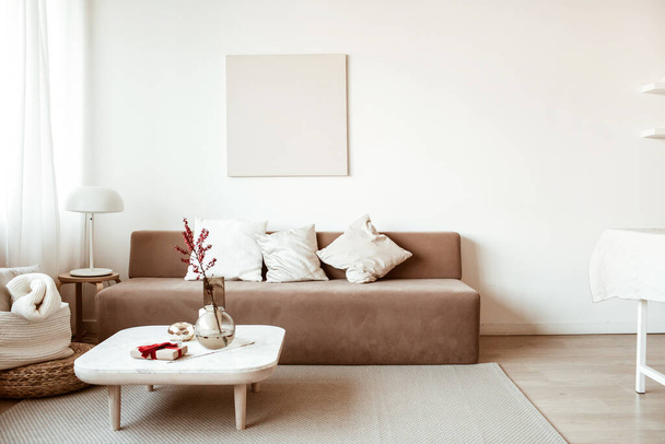 Modern iç tasarım. Rahat kanepe, sehpa, çiçekler, tablolar ve beyaz duvarlarla dekore edilmiş şık bir oturma odası. Kiralık minimalist bir daire. - Fotoğraf, Görsel