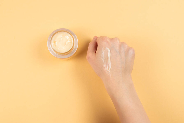 Hand cream and woman hands on a beige background. Copy space.  - Photo, Image