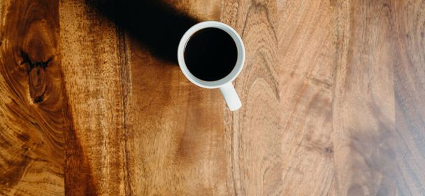 Eine weiße Tasse Kaffee auf dem Holztisch. - Foto, Bild