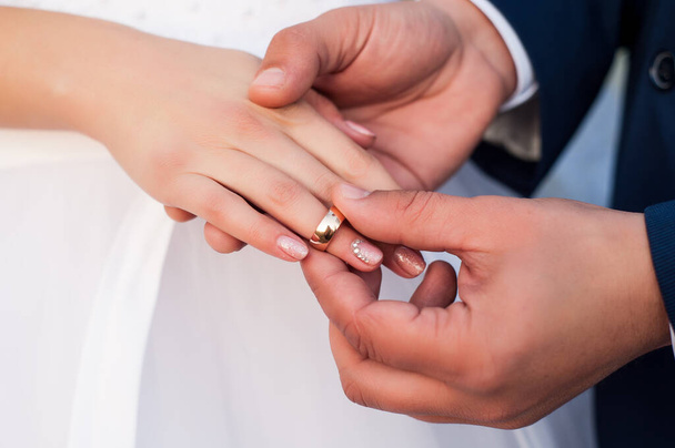 ve svatební den, manžel nasadí snubní prsten nevěstě v bílých šatech a je to štěstí, když se dvě milenecká srdce sjednotí v rodině - Fotografie, Obrázek
