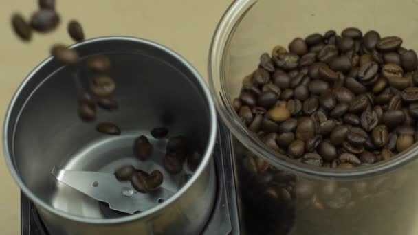 Kávová zrna padají v elektrickém mlýnku, béžové pozadí. Energetický ranní koncept - Záběry, video