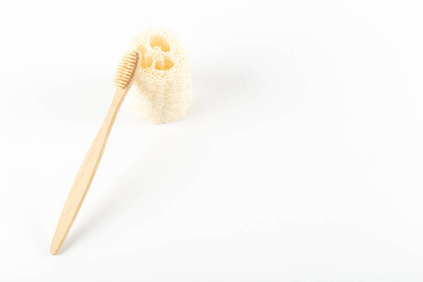 Toothbrushes made of eco materials, made of natural wood lie next to the loofah. On white background. - Photo, image