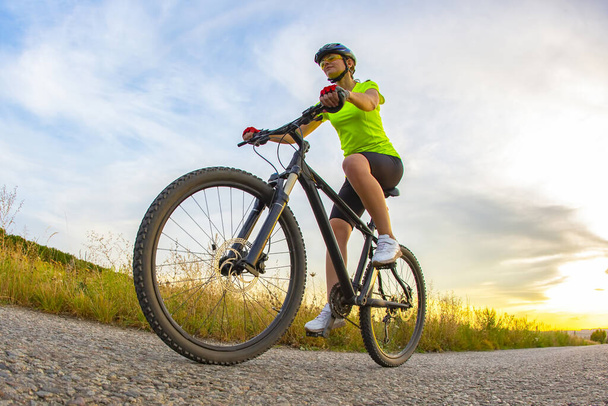 Спортивный красивый велогонщик ездит на велосипеде по дороге на фоне красивой природы. хобби и спорт
 - Фото, изображение