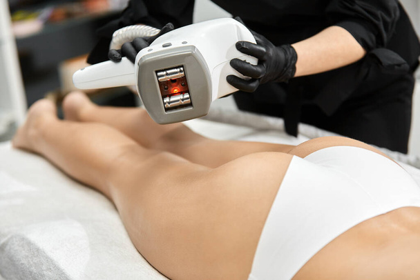 primer plano de los brazos del médico que sostiene el dispositivo de cosmetología sobre el cuerpo femenino, terapeuta con masajeador lpg. esteticista con aparato de endosfera
 - Foto, imagen
