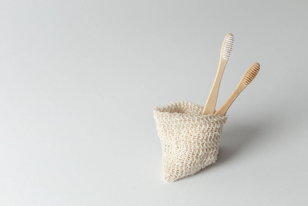 two natural wood toothbrushes lie next to each other in an environmental bag. zero waste. on a gray background. - Fotoğraf, Görsel