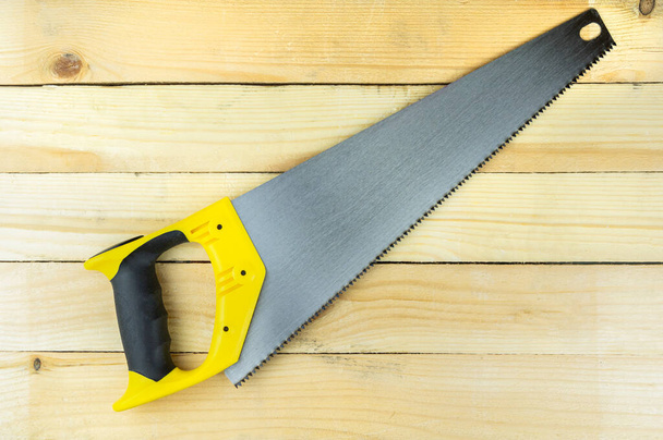 hand saw on wooden background, carpenter's tool, woodworking tool - 写真・画像