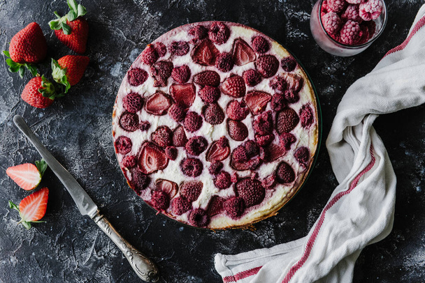Cheesecake με φράουλες και σμέουρα σε σκούρο φόντο.  - Φωτογραφία, εικόνα