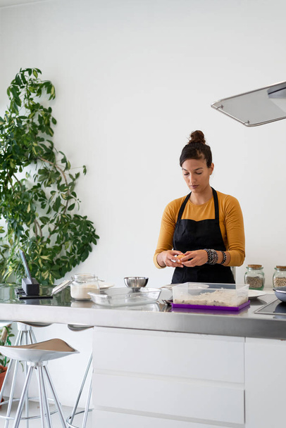 Modern bir mutfakta dijital tabletten yemek pişiren esmer kadın. - Fotoğraf, Görsel