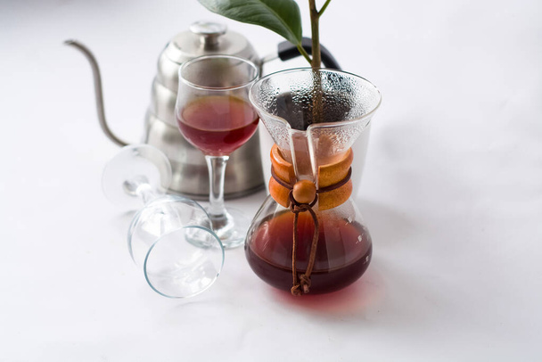 Weißer Hintergrund, Weingläser und schwarzer, kräftiger, morgendlicher, frischer Kaffee im Glasbehälter zur alternativen Zubereitung. - Foto, Bild
