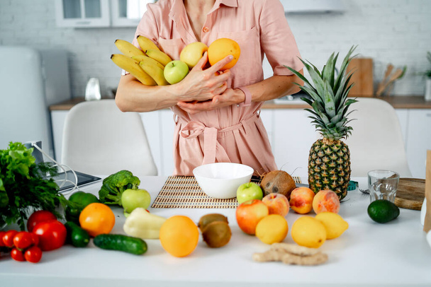 Beautiful young woman holding fresh fruits. Kitchen background at home. Healthy eating concept. Diet, dieting, slimming, weight loss. Healthy lifestyle. - Fotoğraf, Görsel