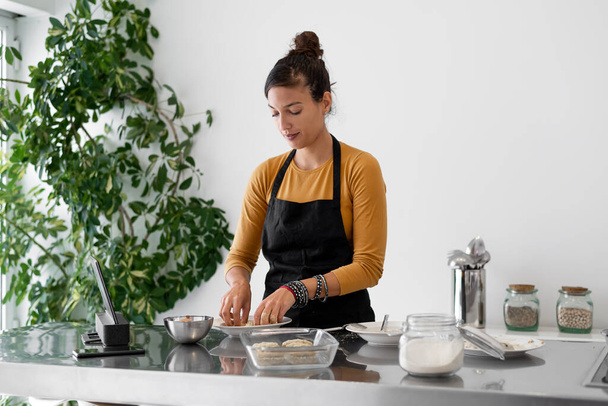 Modern bir mutfakta dijital tabletten yemek pişiren esmer kadın. - Fotoğraf, Görsel