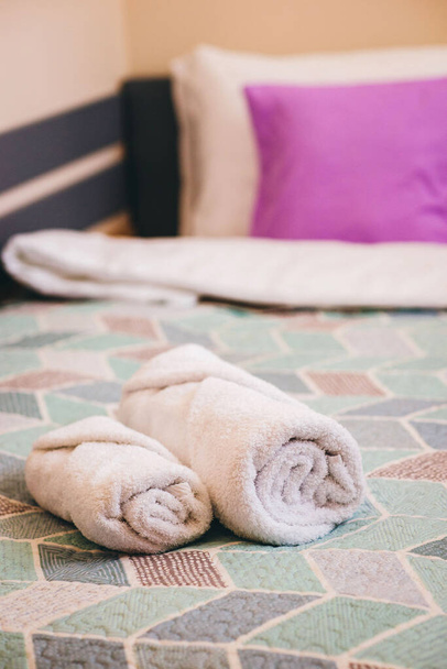 Φρεσκοπλυμένες χνουδωτές πετσέτες στο κρεβάτι στο ξενοδοχείο. - Φωτογραφία, εικόνα