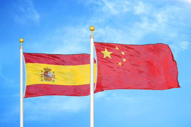 Spain and China two flags on flagpoles and blue cloudy sky background - Photo, Image