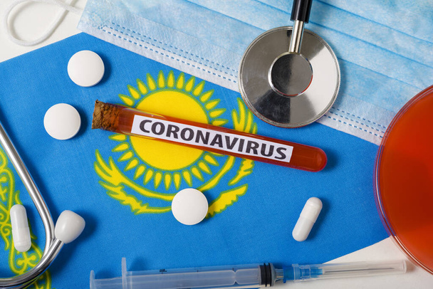 Coronavirus, concepto nCoV. Vista superior máscara respiratoria protectora, estetoscopio, jeringa, tabletas en la bandera de Kazajstán. Un nuevo brote del coronavirus chino
 - Foto, Imagen