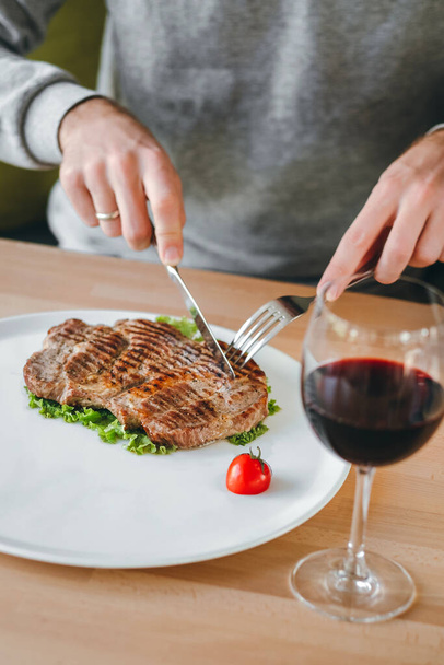 Man's hands eating meat grilled steak, salad and cherry tomato with a glass of red wine - Fotografie, Obrázek