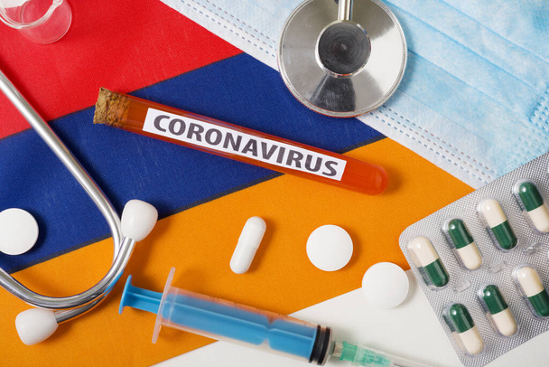 Coronavirus, nCoV-concept. Bovenaanzicht beschermende ademhalingsmasker, stethoscoop, spuit, tabletten op de vlag van Armenië. Een nieuwe uitbraak van het Chinese coronavirus - Foto, afbeelding