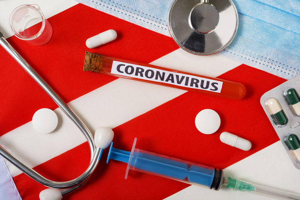 Coronavírus, conceito nCoV. Visão superior máscara respiratória protetora, estetoscópio, seringa, comprimidos na bandeira da Áustria. Um novo surto do coronavírus chinês
 - Foto, Imagem