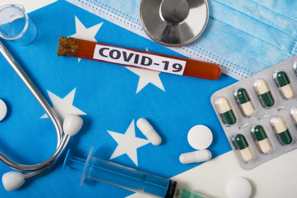 Coronavirus, COVid-19 konsepti. Üst düzey koruyucu solunum maskesi, steteskop, şırınga, mikronezya bayrağında tabletler. Yeni bir Çin Coronavirüsü salgını. - Fotoğraf, Görsel