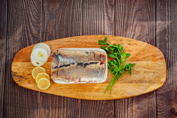 sliced salted herring on plate onion lemon - Fotoğraf, Görsel