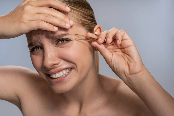 Emotional blonde female person doing eyebrows correction - Фото, зображення