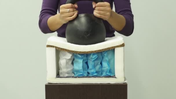 Kobieta kładzie duży ciężar na materacu z pianki ortopedycznej ze sprężyną slow-mo - Materiał filmowy, wideo