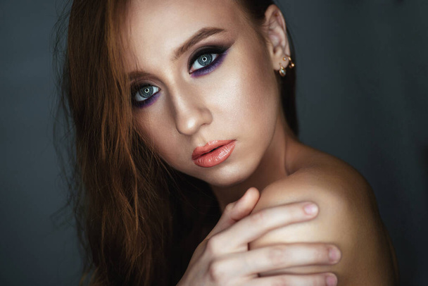 Portrait of a young woman with beautiful evening make-up on a dark background - Photo, Image