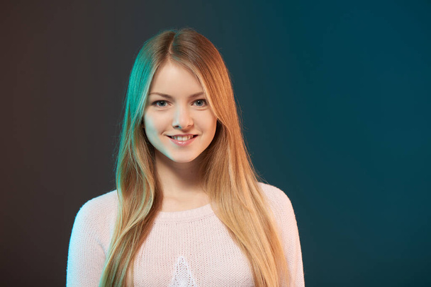 Young smiling female with colorful backlight, closeup studio portrait - Foto, Imagem