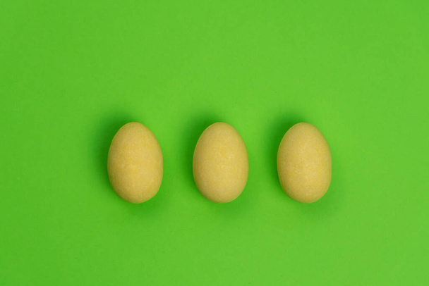 A yellow Easter eggs isolated on a green background. Minimal, top view. - Photo, Image