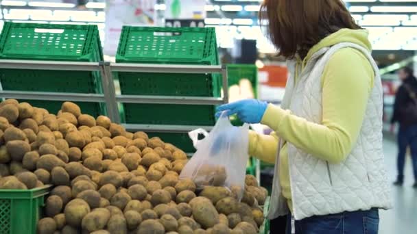Female customer in mask buying potatoes at grocery store during pandemic - Кадри, відео