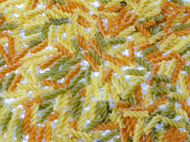 multi-colored pasta scattered on the kitchen table. colorful abstract background - Foto, imagen