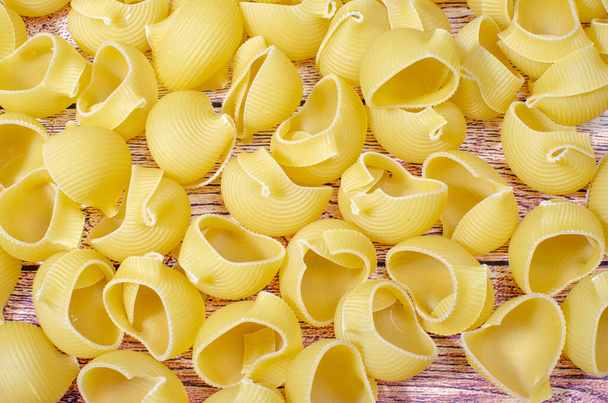 italian yellow pasta on a wooden table, closeup - Fotó, kép
