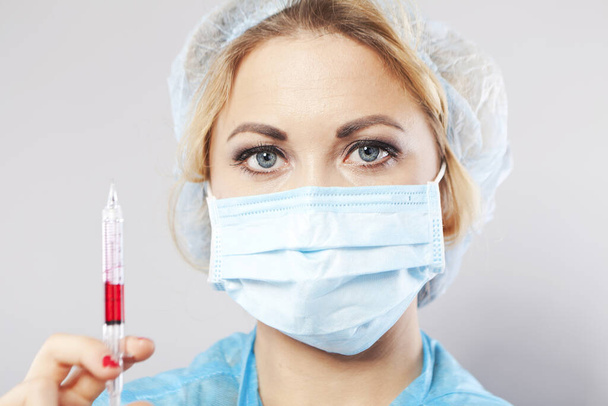 Verpleegster met een medisch masker met een vaccin in haar handen. Portret van een medisch assistent. Medisch werker. - Foto, afbeelding