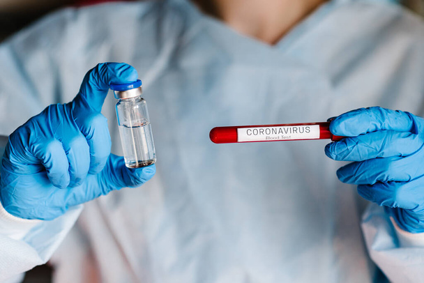Doctor, nurse, scientist holds a test tube with a sample of the patient's blood and a vaccine for the disease. Use for prevention and treatment from coronavirus infection. (COVID-19, 2019-nCoV). - Фото, изображение