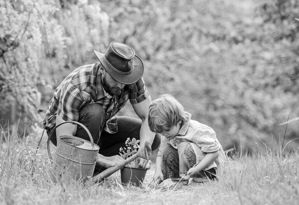 Little helper in garden. Make planet greener. Growing plants. Take care of plants. Day of earth. Boy and father in nature. Gardening tools. Planting flowers. Dad teaching little son care plants - Fotoğraf, Görsel