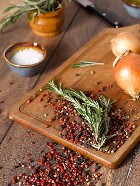 Red pepper, rosemary and onions on a wooden cutting board. - Φωτογραφία, εικόνα