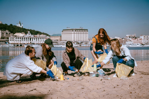 Eine Gruppe befreundeter Aktivisten sammelt Plastikmüll am Strand. Umweltschutz. - Foto, Bild