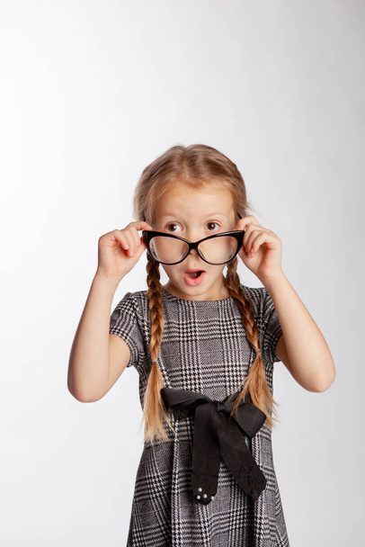 lány egy szigorú szürke ruha egyenesíti szemüveg az orrán - Fotó, kép
