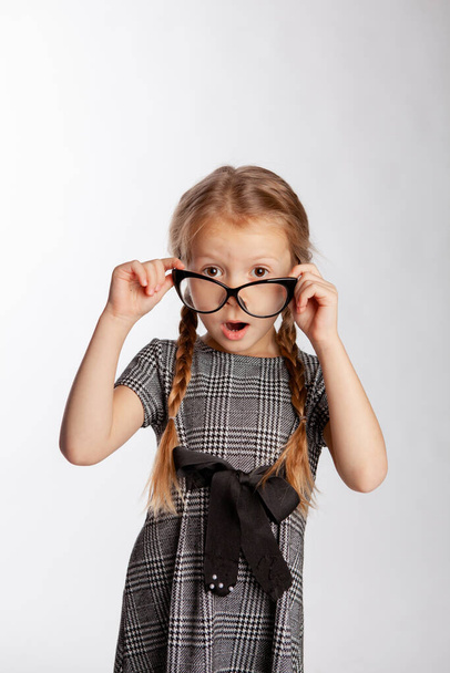 menina em um vestido cinza rigoroso endireita óculos em seu nariz
 - Foto, Imagem