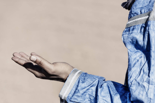 Nyílt kéz egy hagyományos öltözött marokkói embertől. Magas kulcs kép néma színekkel. - Fotó, kép