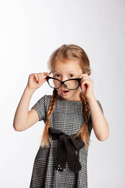 menina em um vestido cinza estrito segura óculos em suas mãos
 - Foto, Imagem