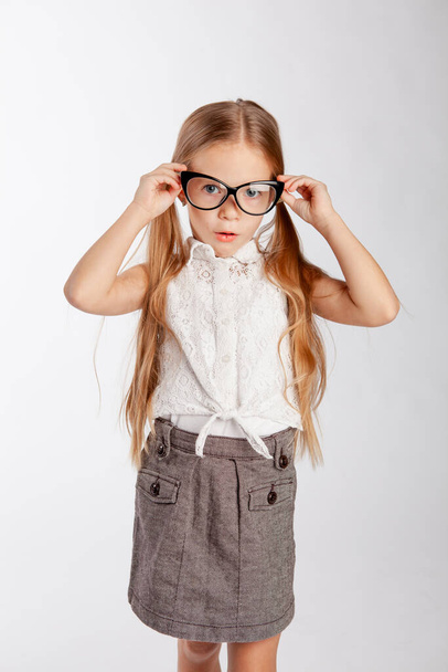  tyttö tiukka harmaa hame ja valkoinen pusero suoristaa lasit nenäänsä
 - Valokuva, kuva